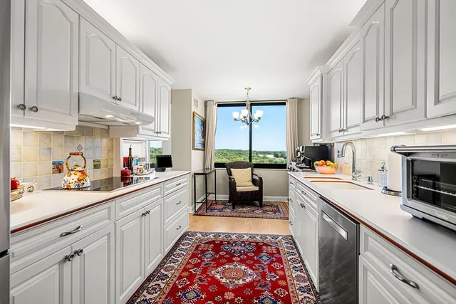 a kitchen with kitchen island granite countertop a sink dishwasher stove and white cabinets with wooden floor