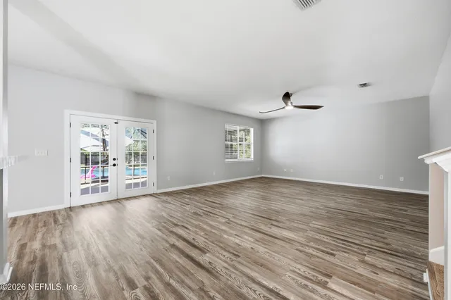 an empty room with wooden floor and windows
