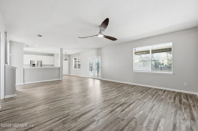 a view of an empty room with window and wooden floor