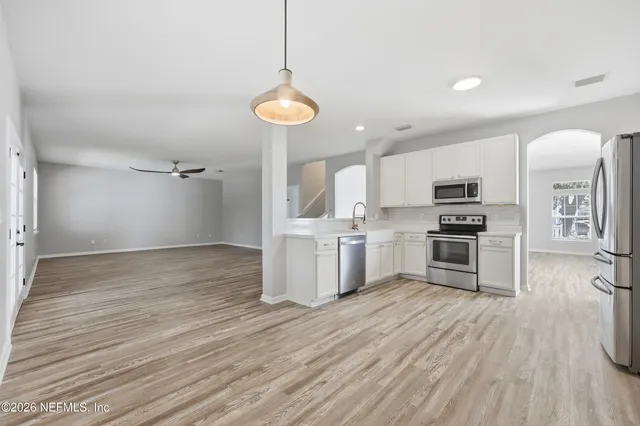 a kitchen with stainless steel appliances a stove top oven a refrigerator cabinets and wooden floor