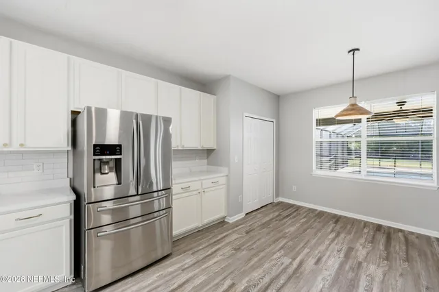 a kitchen with a refrigerator stainless steel appliances wooden floor and window