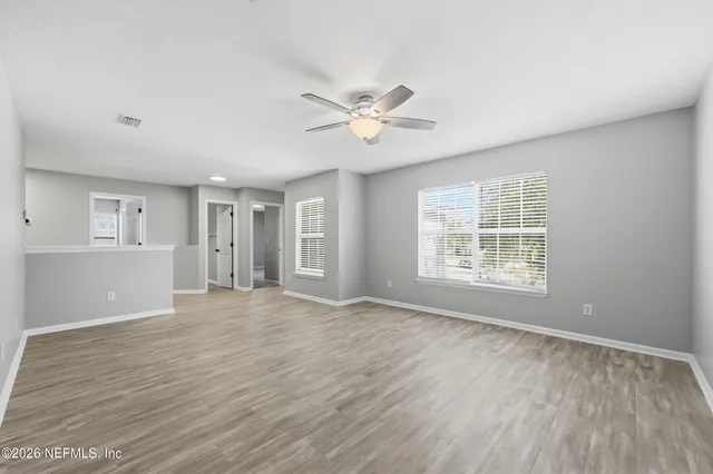 a view of an empty room with a window and wooden floor