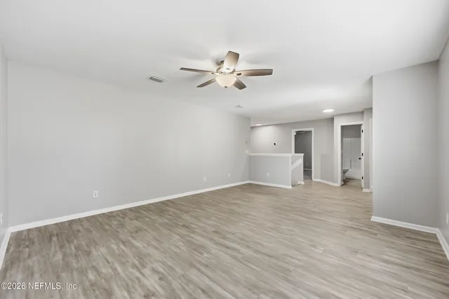 a view of a room with wooden floor and a ceiling fan