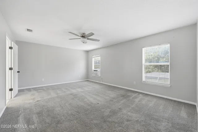 an empty room with a window and a fan