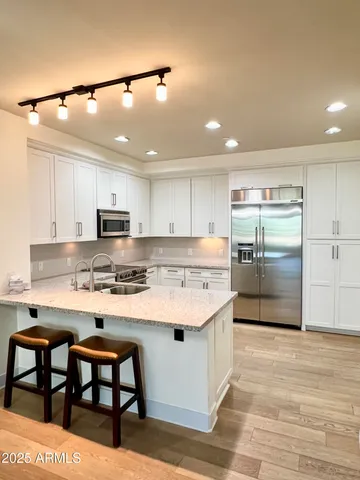 a kitchen with stainless steel appliances kitchen island granite countertop a table chairs refrigerator and microwave