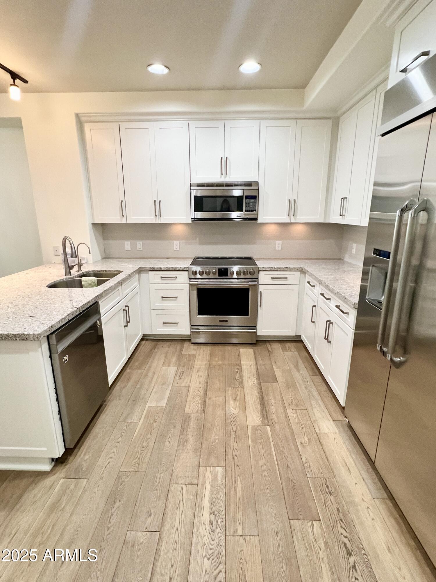 4803 North Woodmere Fairway, Unit 1004 Scottsdale, AZ 85251 - Photo 7 of 21 a kitchen with granite countertop a stove top oven sink and cabinets