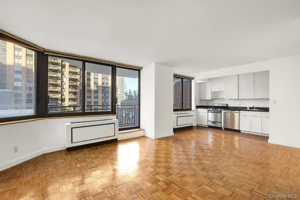 a large living room with stainless steel appliances wooden floor and a large window