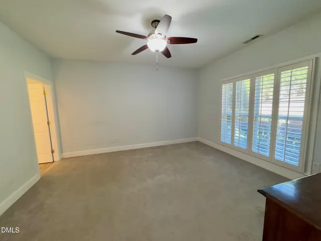 an empty room with fan and windows