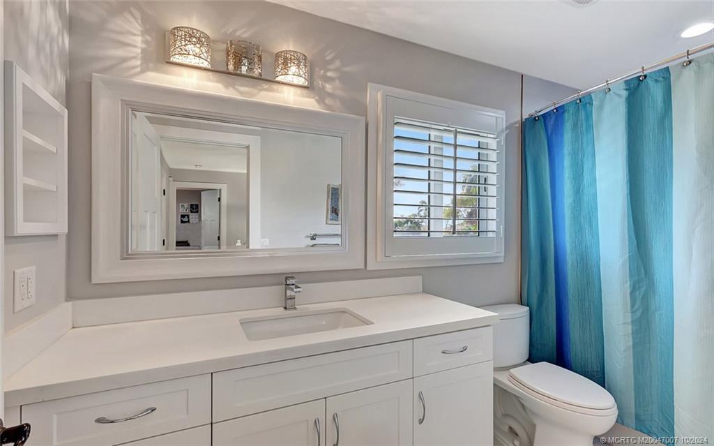 26 Rio Vista Drive Stuart, FL 34996 - Photo 36 of 58 a bathroom with a sink a mirror a toilet and a window