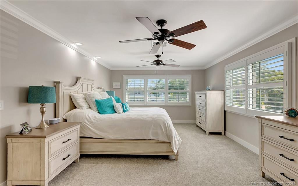 26 Rio Vista Drive Stuart, FL 34996 - Photo 39 of 58 a spacious bedroom with a bed a window and a chandelier