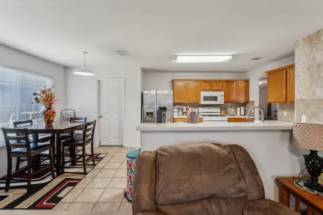 a living room with furniture a rug kitchen view and a large window