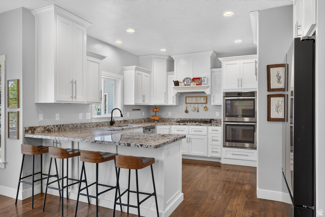 1263 East 1200th South Springville, UT 84663 - Photo 7 of 60 Modern kitchen featuring white cabinetry, stone countertops, stainless steel double wall ovens, a large island with bar seating, and wood-finish flooring
