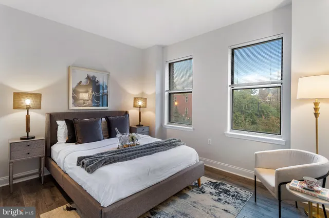 a bedroom with a bed a lamp on dresser and a window