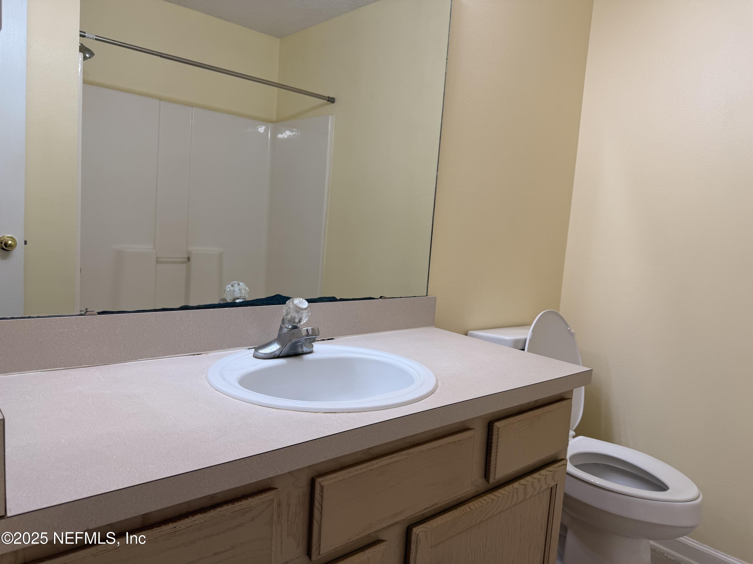 7920 Merrill Road, Unit 810 Jacksonville, FL 32277 - Photo 13 of 14 a bathroom with a sink a toilet and mirror
