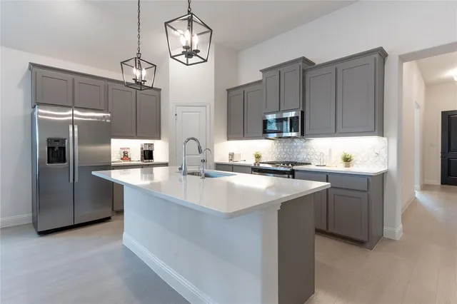 a kitchen with kitchen island granite countertop stainless steel appliances a sink a refrigerator and a stove