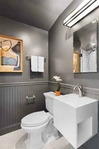 a bathroom with a toilet a sink and mirror