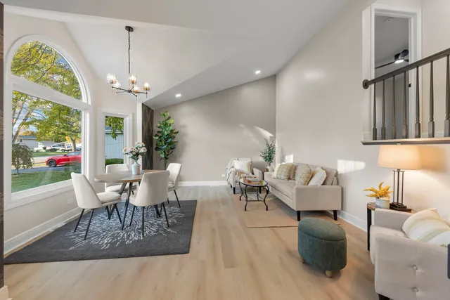 a dining room with wooden floor a chandelier a glass table and chairs