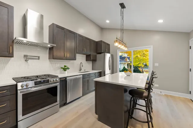 a kitchen with stainless steel appliances granite countertop a stove a sink a refrigerator a stove and white cabinets with wooden floor