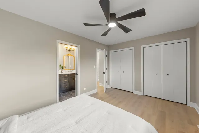 a bedroom with a large bed and a chandelier fan