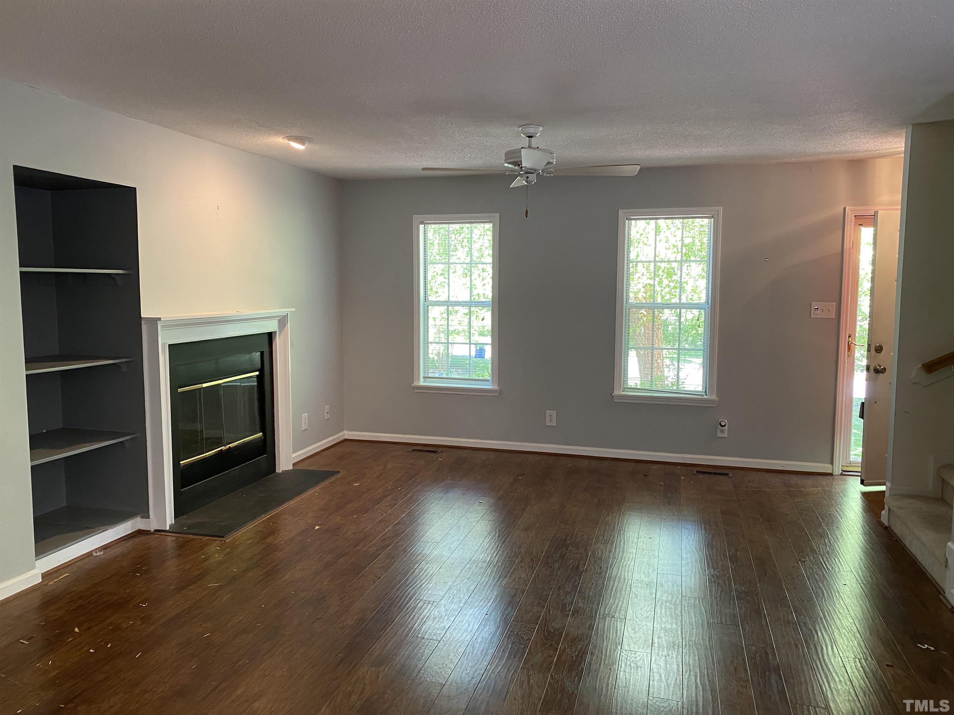 116 Baldwin Drive Durham, NC 27712 - Photo 9 of 33 an empty room with wooden floor fireplace and windows