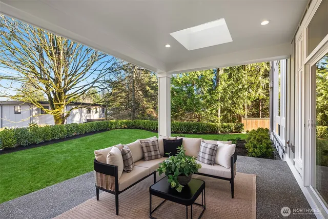 a view of a patio with couches plants and large trees
