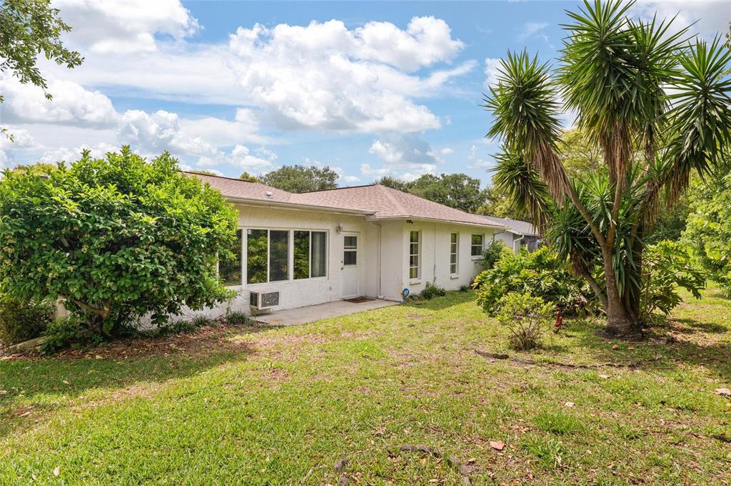 11241 Rollingwood Drive Port Richey, FL 34668 - Photo 26 of 26 a view of a house with a small yard and palm trees