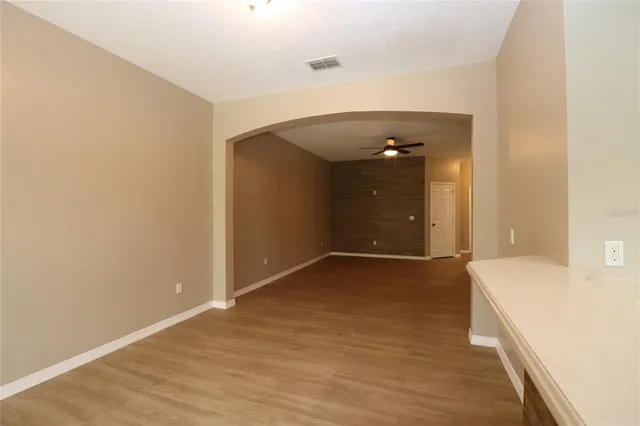 a view of an empty room with wooden floor and a bathroom