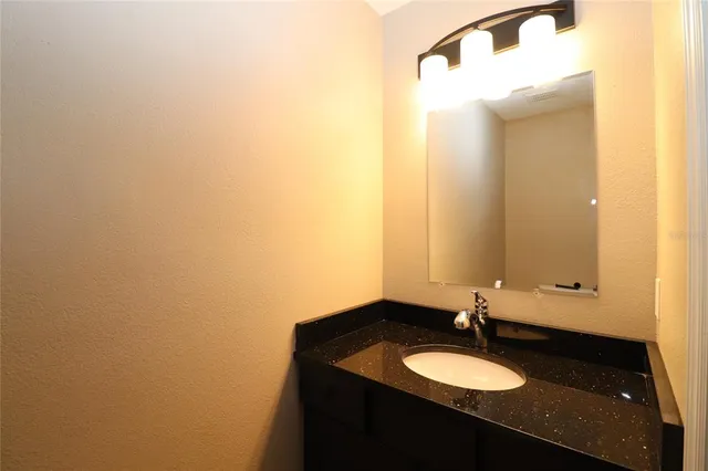 a bathroom with a granite countertop sink and a mirror