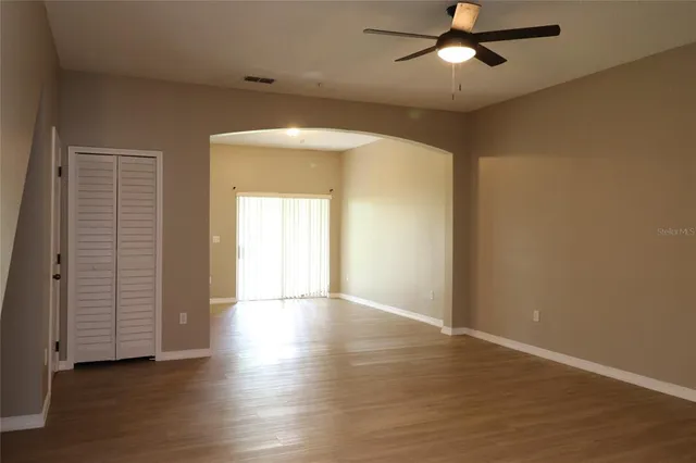 an empty room with wooden floor closet and windows
