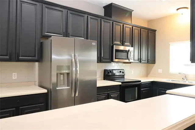 a kitchen with granite countertop a refrigerator stove top oven and sink