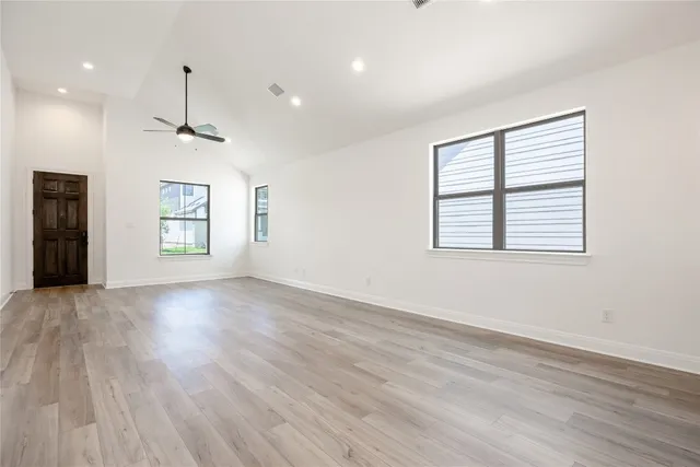 a view of an empty room with a window and wooden floor