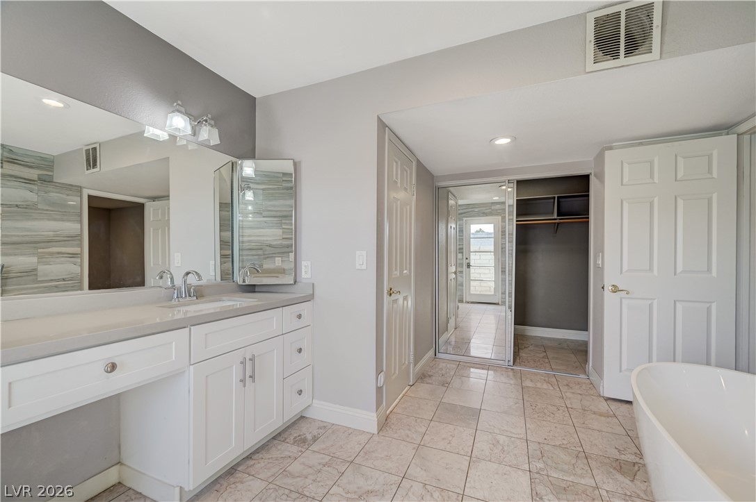6635 Costa Brava Road Las Vegas, NV 89146 - Photo 32 of 59 A chic master bathroom featuring a contemporary vanity with dual sinks, sleek mirrors, and elegant tiled flooring.
