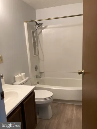 a bathroom with a granite countertop bathtub shower sink vanity and toilet