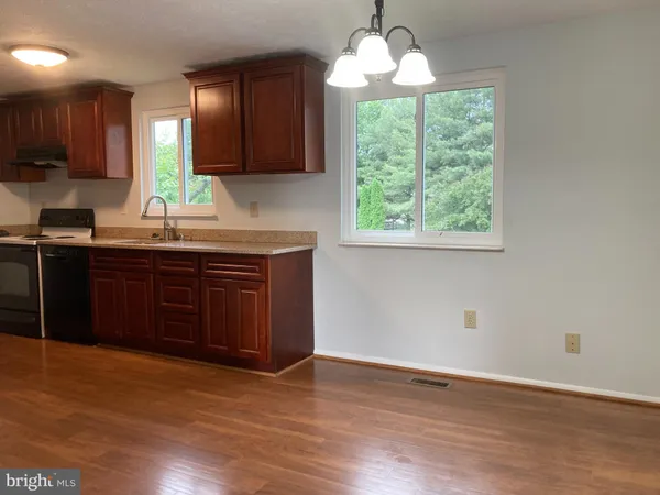 a kitchen with stainless steel appliances granite countertop wooden cabinets and a large window