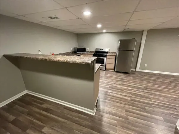a view of kitchen with refrigerator stove and wooden floor