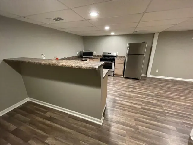 a view of kitchen with refrigerator stove and wooden floor