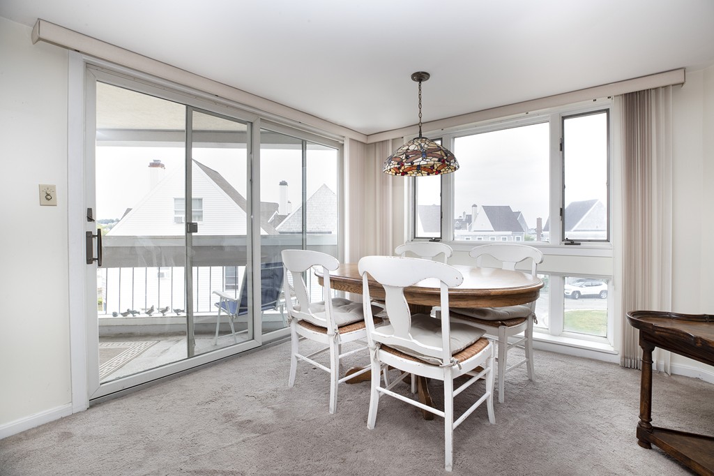 304 Commodore Court, Unit 304 Hull, MA 02045 - Photo 4 of 12 a dining room with furniture large windows and a chandelier