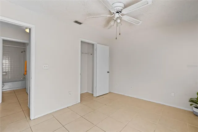 an empty room with a ceiling fan and carpet
