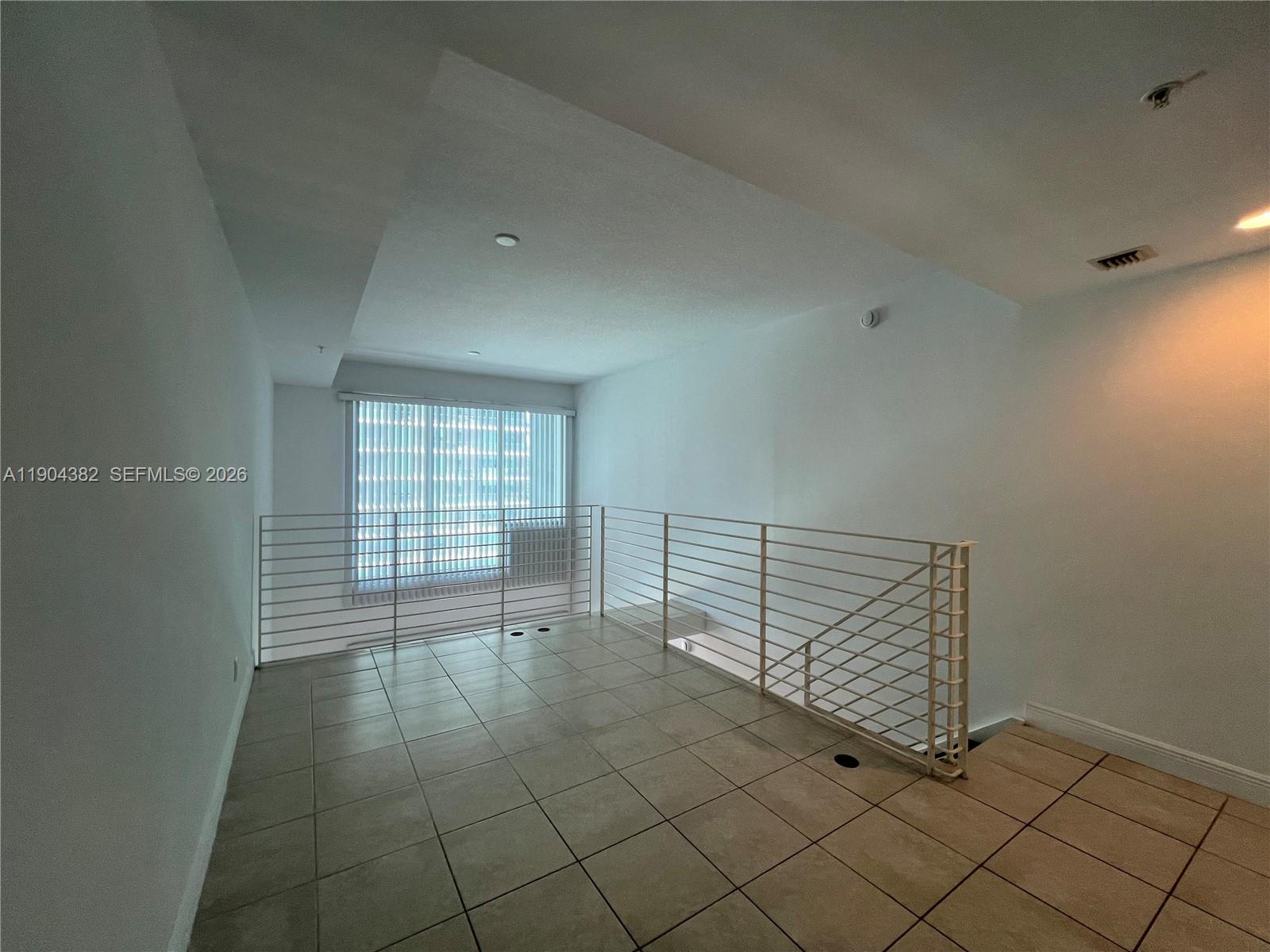 60 Southwest 13th Street, Unit 1612 Miami, FL 33130 - Photo 10 of 24 a view of an empty room with wooden floor and a window