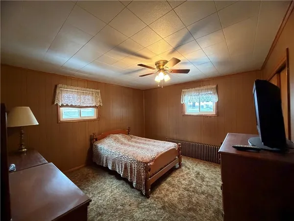 a bedroom with a bed dresser and a flat tv screen