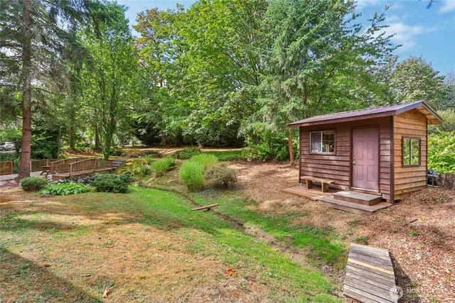 an aerial view of a residential houses with outdoor space and trees all around