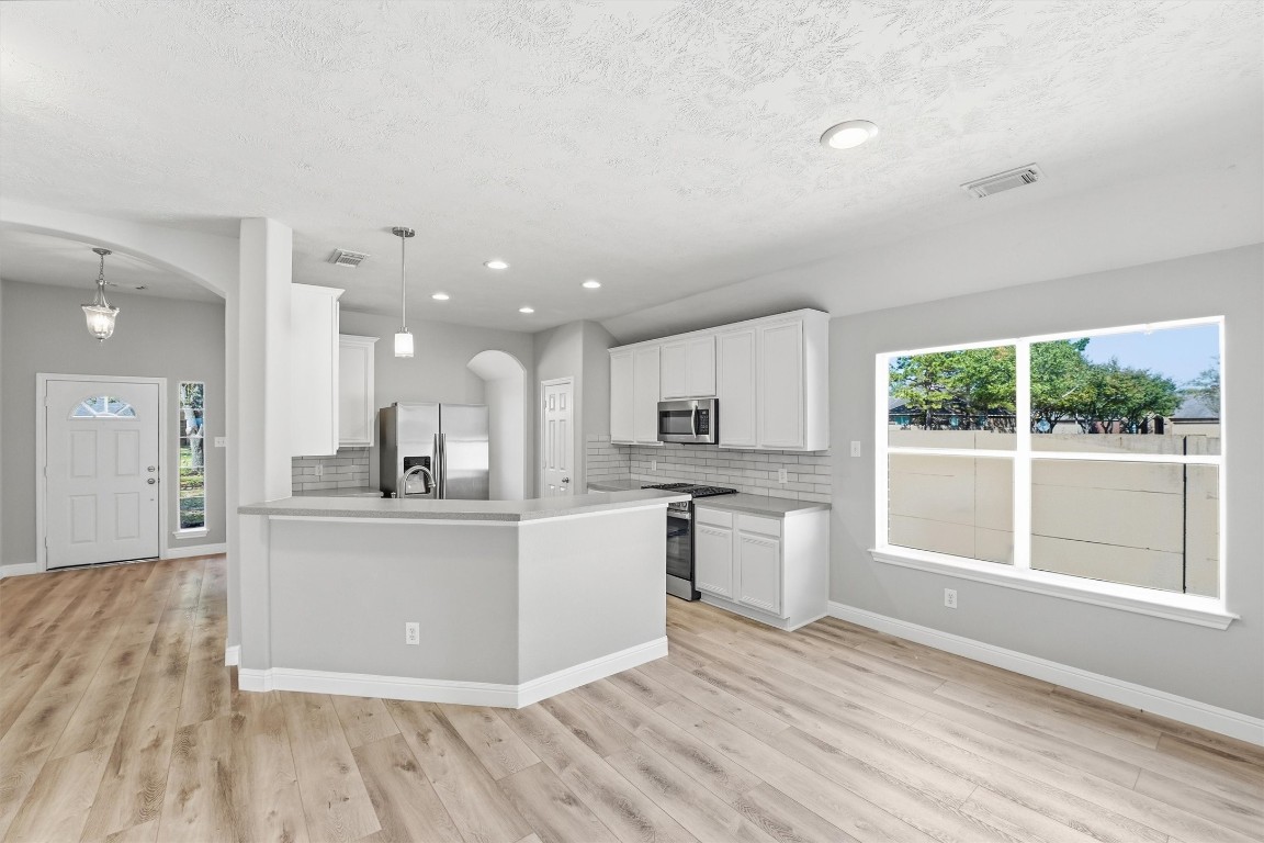 23301 Tuttle Court Porter, TX 77365 - Photo 15 of 50 a view of kitchen with stainless steel appliances granite countertop a stove top oven a sink dishwasher a refrigerator and white cabinets with wooden floor