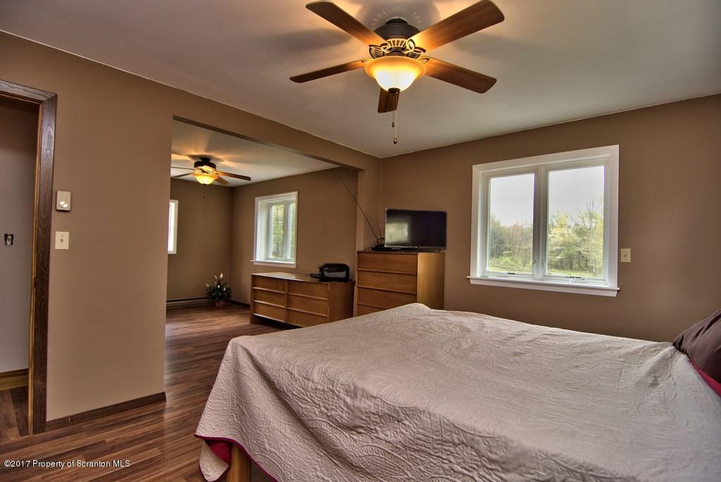 5275 Bloomington Road Moscow, PA 18444 - Photo 37 of 48 a bedroom with a large bed and a chandelier