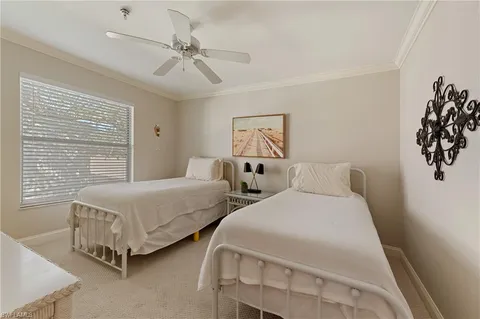 a bedroom with two beds and ceiling fan