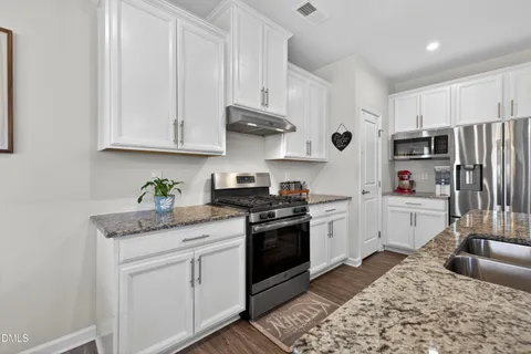 a kitchen with stainless steel appliances granite countertop a refrigerator sink and stove