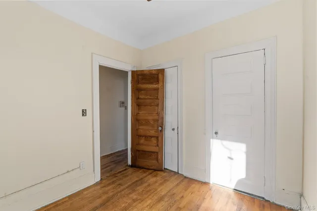 a view of an empty room with closet and wooden floor