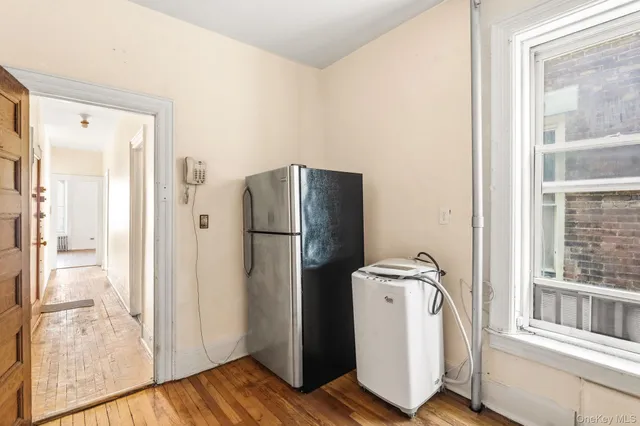 a view of a kitchen with refrigerator and wooden floor