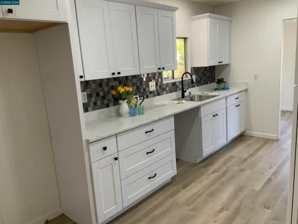 an empty room with wooden floor cabinet and windows