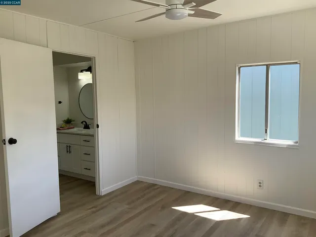 an empty room with wooden floor cabinet and windows