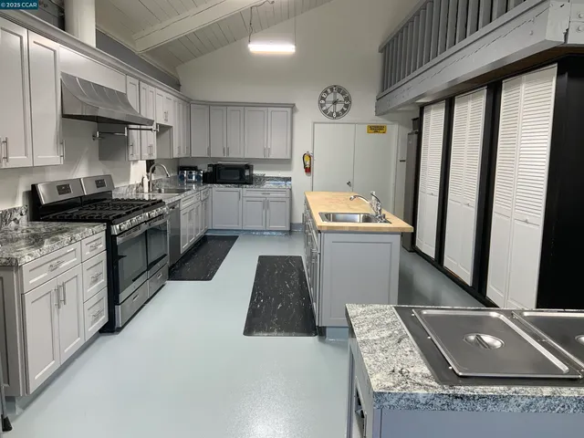 a kitchen with granite countertop a sink stainless steel appliances and white cabinets